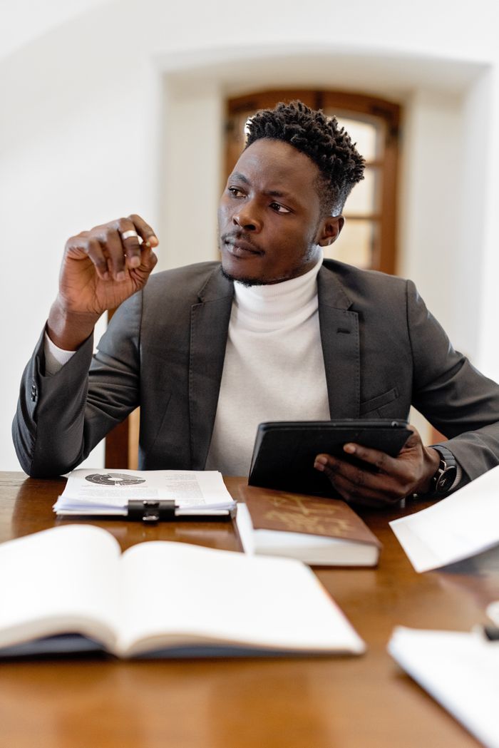 Designing the Future: The Critical Role of Advanced Data Analytics in Crafting Uganda's Next-Gen Public Policies Confident black male professional in office setting consulting a tablet.