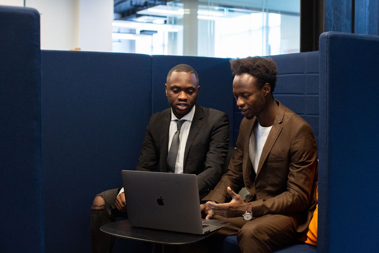 Two business professionals engaged in a collaborative discussion using a laptop in a modern office space.