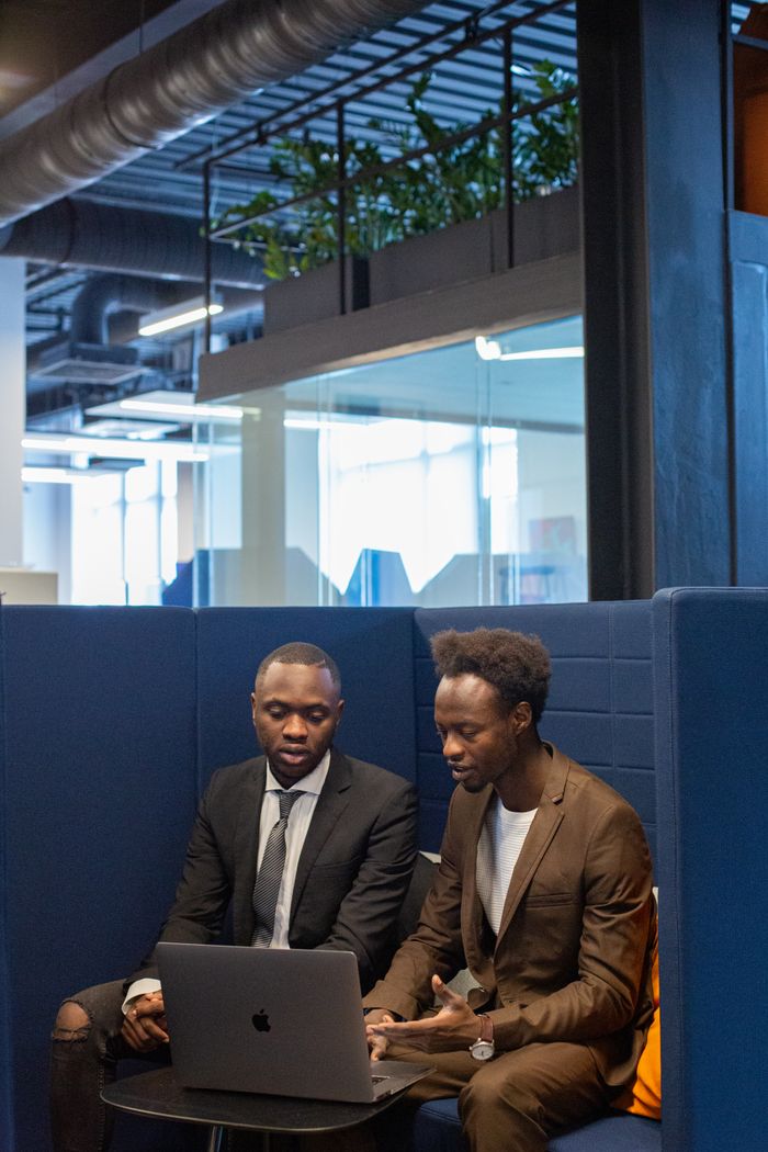 Two men engaged in a business discussion at a laptop in a modern office.